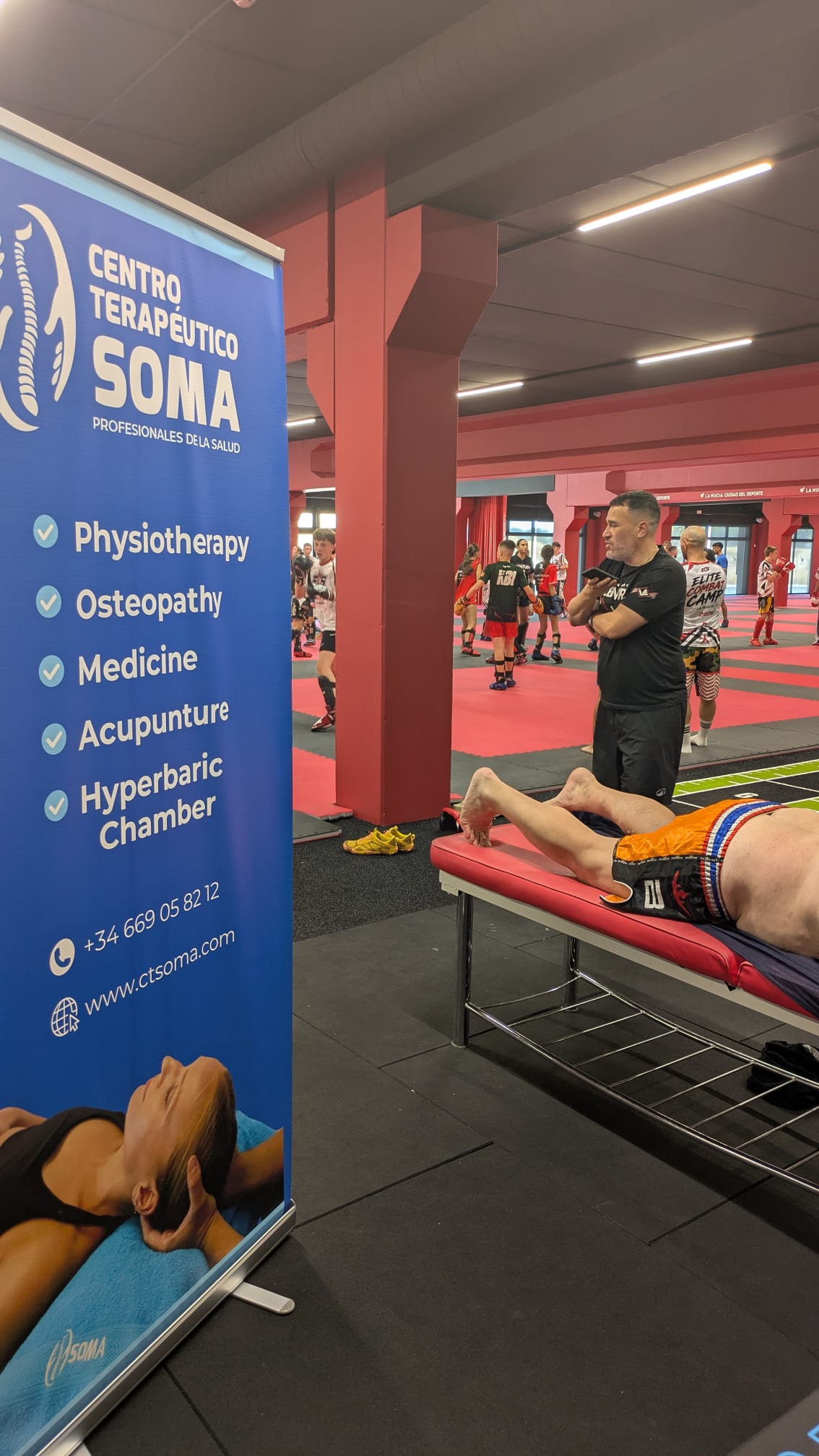 Fisioterapeuta del Centro Terapéutico SOMA atendiendo a un deportista en el Summer Camp de kick boxing de La Nucía